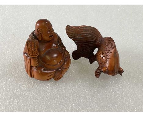 Two boxwood netsuke carved as a Buddha and a fish.