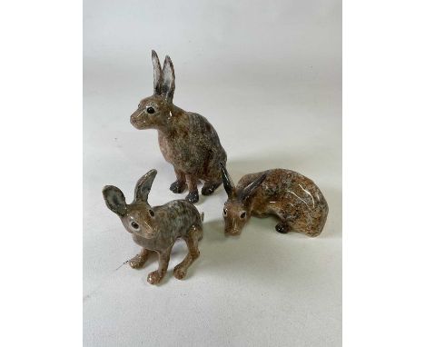 WINSTANLEY; a collection of three ceramic hares with amber eyes in mottled brown glaze, two seated and one lying down, the tw