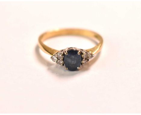 An 18ct yellow gold dress ring set with six round brilliant cut small diamonds and centred with a pale blue stone, size R, ap