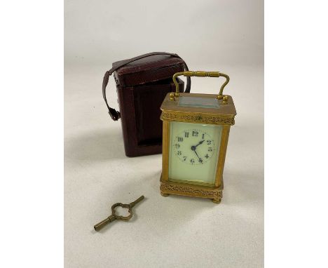 A brass carriage clock with pierced decoration to the case, the enamelled dial set with Arabic numerals, height 12cm, with ke