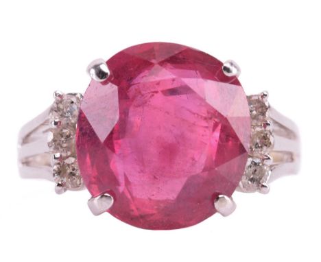 A ruby and diamond ring, the four-claw set oval cut ruby approximately 12.5mm x 11.5mm, the trifurcated shoulders each set wi