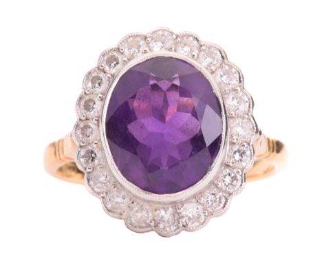 An amethyst and diamond halo ring, featuring an oval-cut amethyst of 11.7 x 9.8 x 5.8 mm, collet-set within a scalloped surro