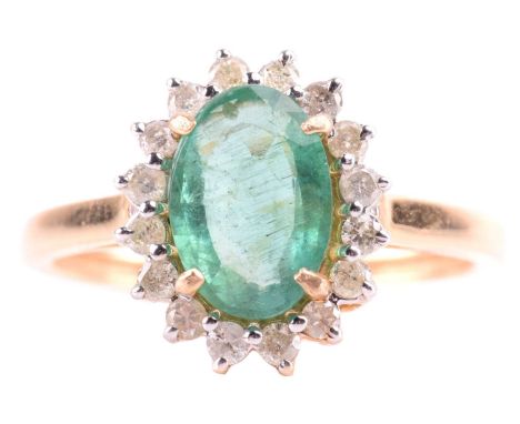 An emerald and diamond halo ring, centred with an oval-cut emerald of pale green colour, approximately measures 9.7 x 6.7 mm,