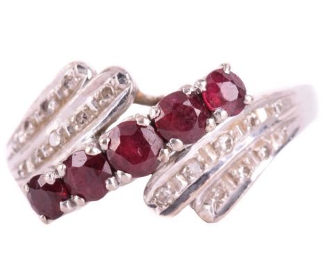 A ruby and diamond crossover ring in 14ct white gold, claw-set with five circular-cut rubies at the centre, with crossover sh