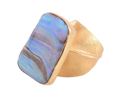 A yellow metal and boulder opal dress ring; the oblique shaped rectangular plaque within a textured mount and set above a tex
