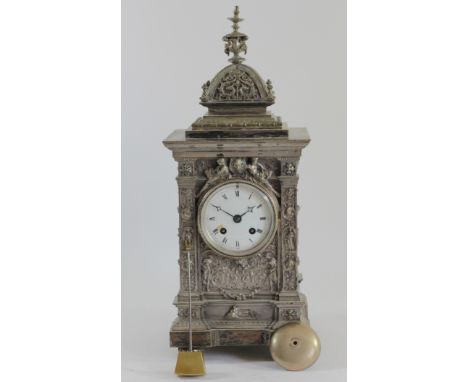A Victorian cast silvered metal ornate mantle clock, white enamel dial to a French movement, the case with two men above the 