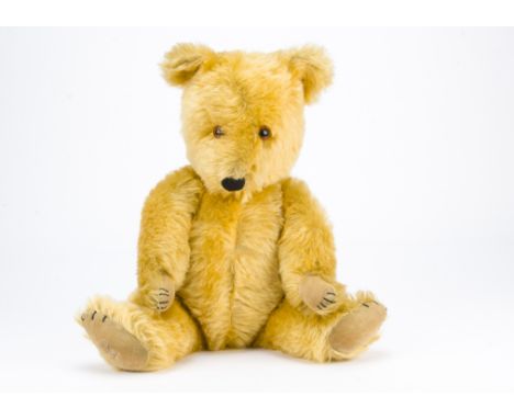 A post-war Chiltern Hugmee teddy bear, With golden mohair, orange and black glass eyes, black stitched nose, mouth and claws,