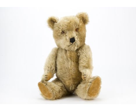 A post-war Chiltern Hugmee teddy bear, With blonde mohair, orange and black plastic eyes, black stitched nose, mouth and claw