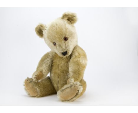 A post-war Chiltern Hugmee teddy bear, With blonde mohair, orange and black glass eyes, black stitched nose, mouth and claws,