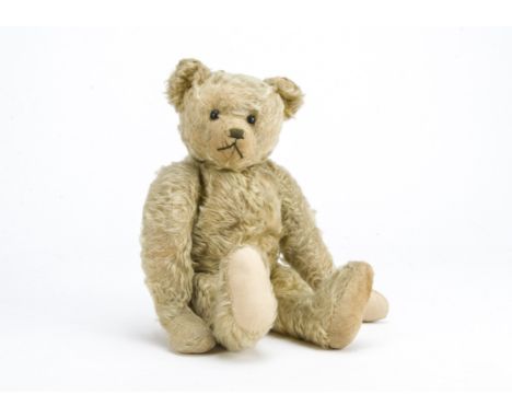 An early British teddy bear circa 1920, with light golden mohair, black boot button eyes, pronounced muzzle, black stitched n