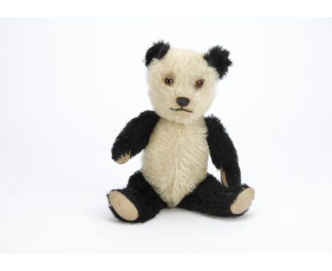 A post-war Chiltern panda teddy bear,  with black and white mohair, orange and black glass eyes, black stitched nose and mout