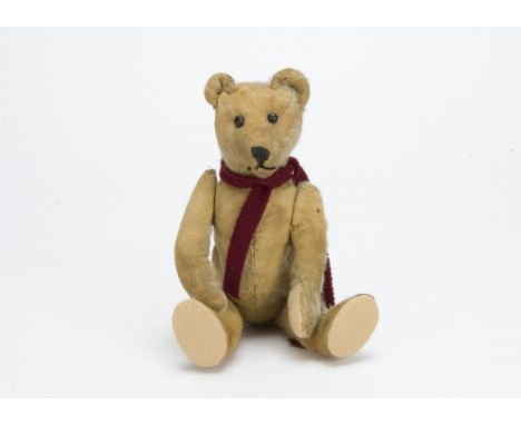 An early German teddy bear circa 1910, with blonde mohair, black boot button eyes, pronounced muzzle, black stitched nose and