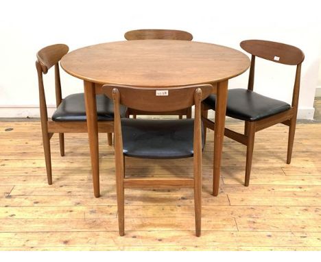 A Vintage mid century teak extending dining table, the circular top pulling to reveal a magic leaf, raised on turned tapering