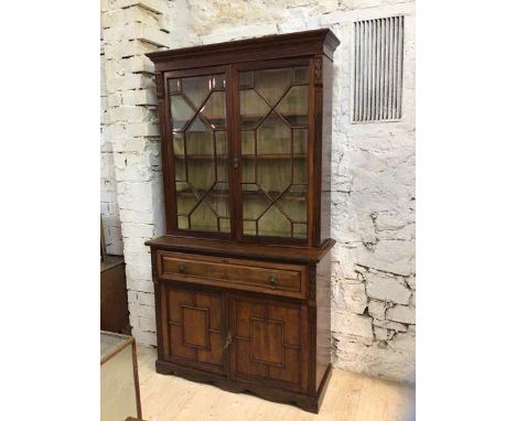 An Edwardian walnut secretaire bookcase, the projecting cornice over astragal bevel glazed doors enclosing three shelves abov