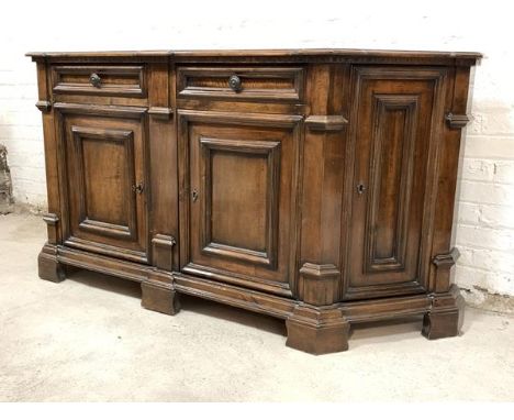 An 18th century design mahogany sideboard of canted rectangular outline, the moulded top over incised frieze, two drawers and