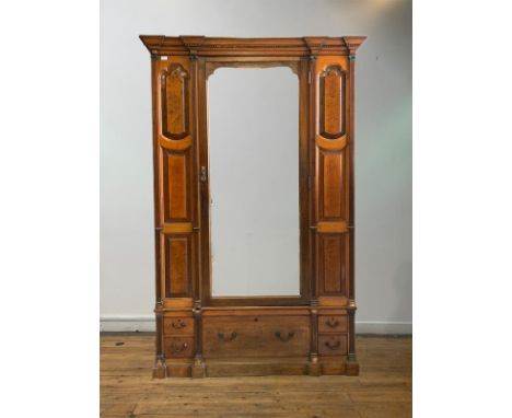 A late 19th/ early 20th century oak wardrobe of architectural form, the dentil cornice over a mirror door opening to reveal a