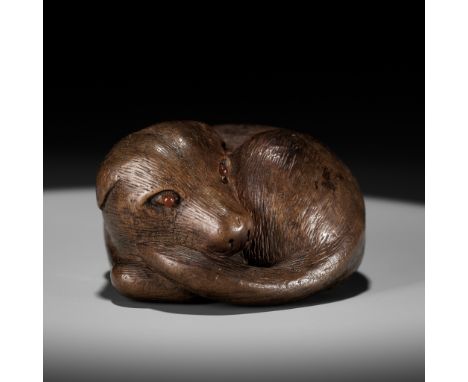 SARI: A SUPERB WOOD NETSUKE OF A RECLINING DOGBy Sari, signed Sari 左里Japan, Iwashiro Province, c. 1800-1820, Edo period (1615