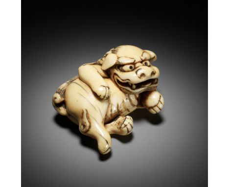 AN AMUSING AND RARE IVORY NETSUKE OF A RECUMBENT SHISHIUnsignedJapan, 18th century, Edo period (1615-1868)The fierce shishi c