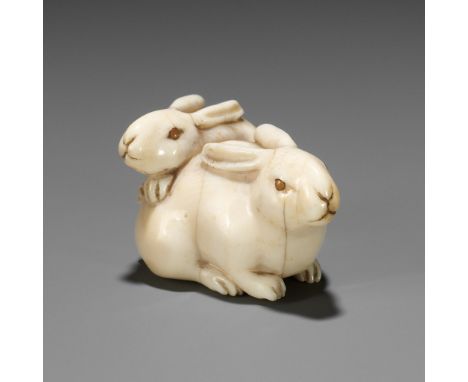 A FINE IVORY NETSUKE DEPICTING TWO RABBITS WITH CORAL-INLAID EYESUnsignedJapan, 19th century, Edo period (1615-1868)Finely ca