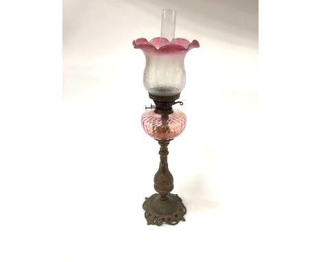 Brass oil lamp with cranberry tinted shade, total height 77cm including shade