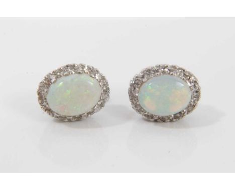 Pair 18ct white gold opal and diamond earrings, each with an oval opal in claw setting surrounded by a border of twelve brill