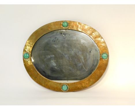 A Liberty &amp; Co oval brass mirror, framed with four Ruskin ceramic roundels, rebacked, 53cm high, 64.5cm wide.