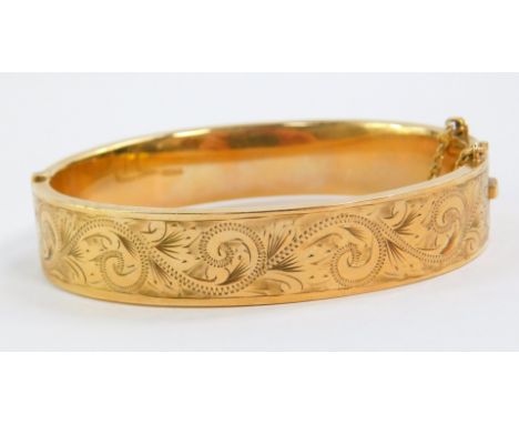 A 9ct gold bangle, foliate engraved, on a snap clasp, with safety chain as fitted, 18.4g.