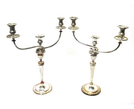 A pair of plated on copper three light table candelabra, each with a faceted tapering stem and with an urn shaped surmount, o