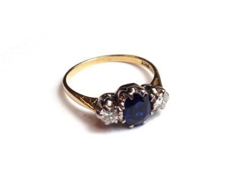 A gold, sapphire and diamond set three stone ring, claw set with the oval cut sapphire at the centre, between two circular cu