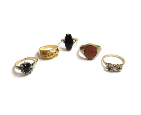 A 9ct gold and goldstone set signet ring, a 9ct gold and colourless gem set ring, a gold and red gem set ring and two further