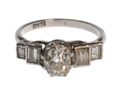 A platinum and diamond set ring, claw set with the principal old cut cushion shaped diamond at the centre, between baguette d