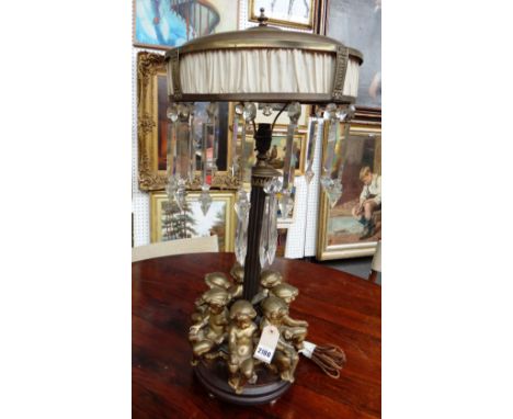 A gilt metal figural table lamp, late 19th century style, the circular upholstered metal shade over a fluted central column s