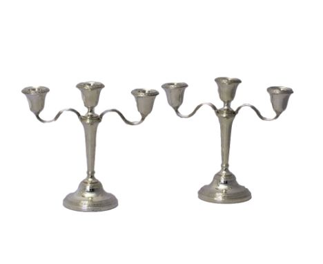 A pair of silver three light table candelabra, each with foliate decorated rims and raised on a circular foot, Birmingham 196