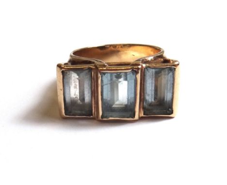 A gold,  aquamarine and pale blue gem set set three stone ring, mounted with a row of three rectangular cut pale blue stones 