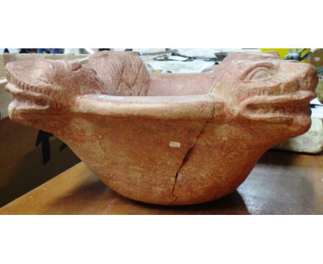 A redstone basin, probably Indian, the circular rim carved with four lion masks, (A.f), 47cm.maximum width.