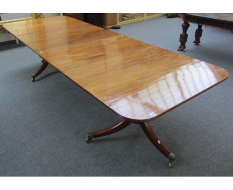A George III and later twin pedestal dining table, the rounded rectangular top with two extra leaves, on pair of tripod bases