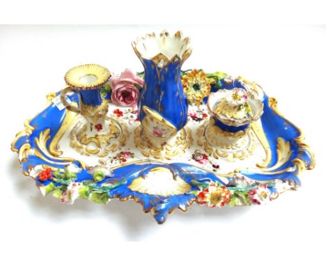 An English porcelain desk stand, circa 1840, with loop handle and shaped foliate encrusted body decorated in blues and yellow
