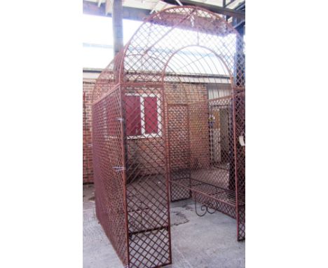 An iron arch top rose arbour with lattice sides and integral bench seats, 196cm wide x 200cm deep x 300cm high. 