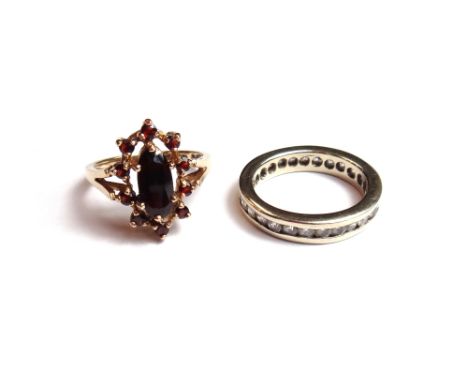A gold and colourless gem set eternity ring, detailed 585, ring size K and a half and a 9ct gold and garnet set oval cluster 