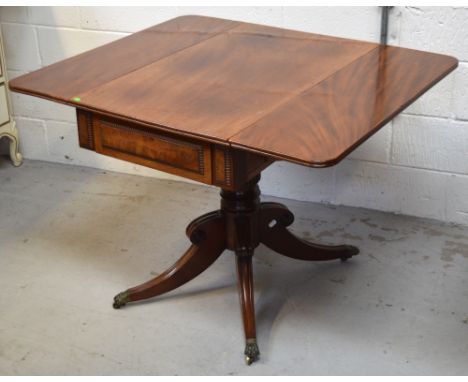 An early 19th century mahogany centre pedestal Pembroke table with moulded decoration to the frieze drawer, central turned co