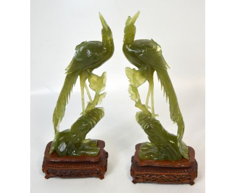A pair of naturalistic modelled carved jade peacocks, unsigned, both presented on heavily carved hardwood bases, each stand w