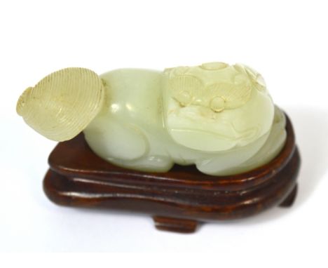 A Chinese pale green jade carved chi chi with russet inclusion to the back and on shaped wooden stand, length 6cm. CONDITION 