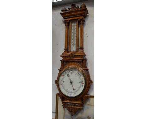 A large heavily carved oak aneroid wall barometer, height 110cm.