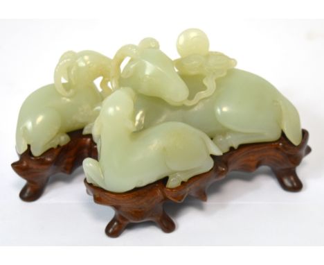 A fine Chinese Qianlong pale green/mutton fat carved jade group modelled as three recumbent rams mounted on a carved rosewood