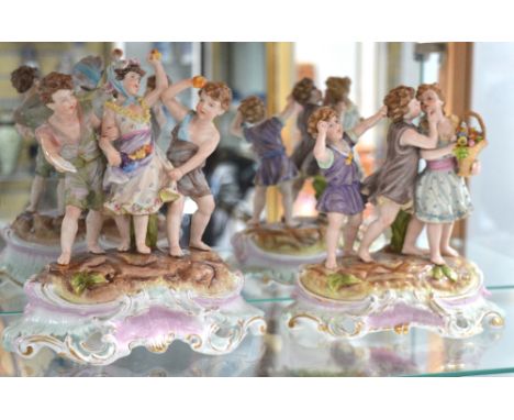 A pair of early 20th century Continental figurines, each of three children on a rocky outcrop, one featuring children kissing