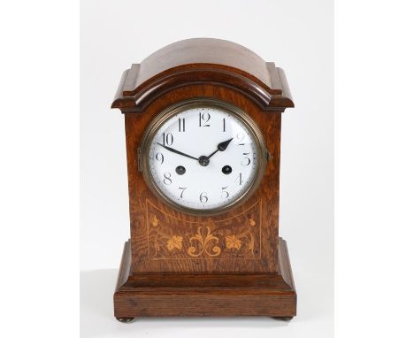 Edwardian oak and marquetry inlaid mantel clock, the arched case with stylised foliate and scroll inlay, the white dial with 