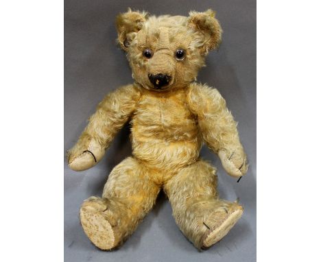 A 1930s Chad Valley teddy bear, having golden mohair body, glass eyes, curved arms and a blank button to the ear, measuring 3