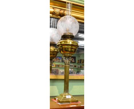A late Victorian brass oil lamp, with glass chimney and floral pattern shade, raised on a reeded column support and stepped b