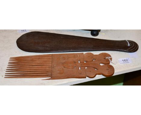 A Maori Patu, of dense hard wood, the grip with overlapping scale carved pommel, 39cm;  a Solomon Islands hair comb, made fro