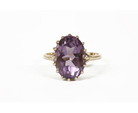 A 9ct rose gold single stone oval cut amethyst ring, claw set to tri-foil shoulders and a plain polished shank, London, 19613